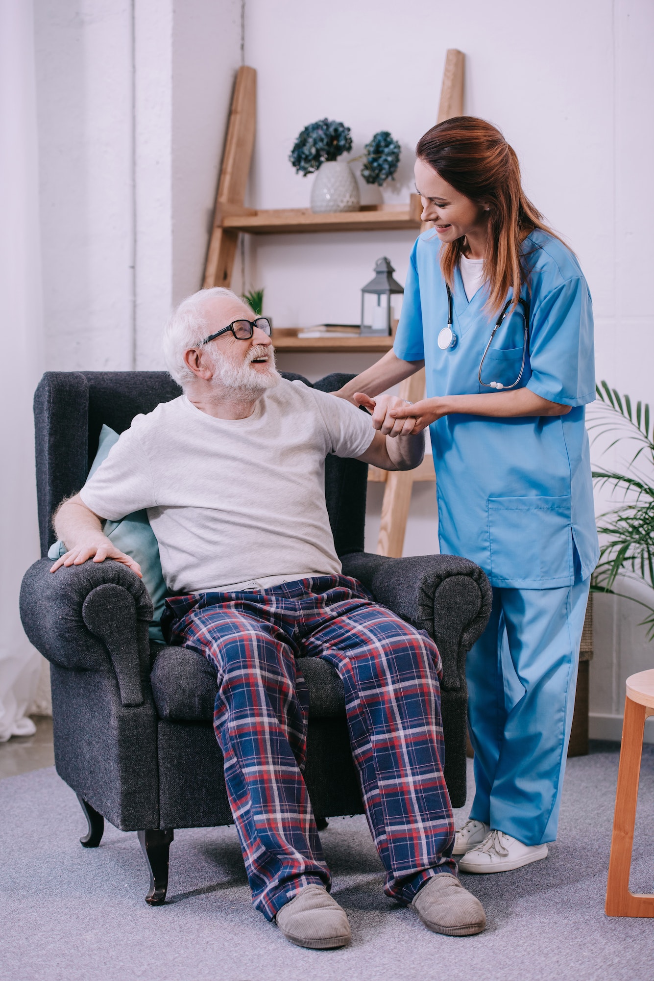 Caregiver holding hand of smiling senior man patient