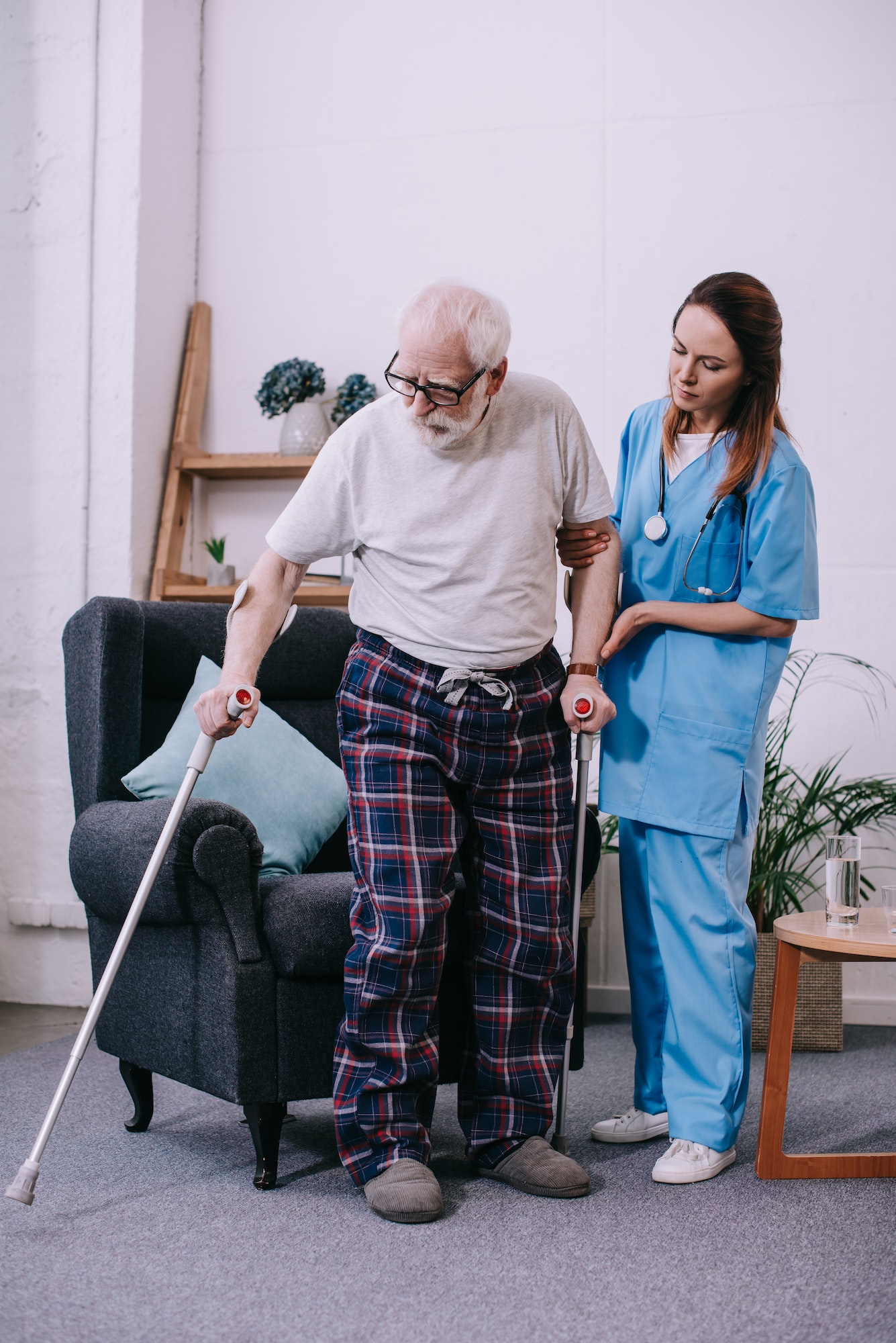 Nurse supporting male patient with crutches